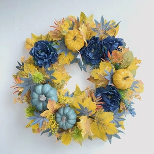 Detailed close-up of blue roses and yellow maple leaves on a decorative pumpkin wreath