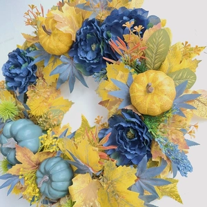 Detailed close-up of blue pumpkins and yellow maple leaves on an autumn wreath