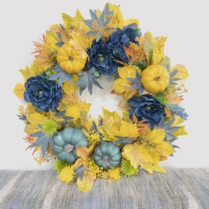 Detailed view of autumn wreath with blue pumpkins, yellow maple leaves and silk flowers