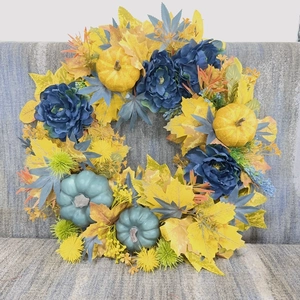 Close-up of harvest wreath with blue pumpkins, yellow maple leaves and thistle decor
