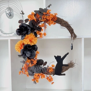 Macro detail of Halloween moon wreath featuring black cat silhouette and orange faux flowers