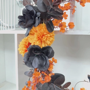 Close-up of Halloween wreath with black velvet roses and bright orange marigold flowers