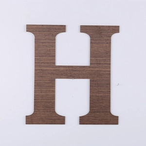 Detail of a dark brown wood grain letter H decorative wall hanging with rustic texture