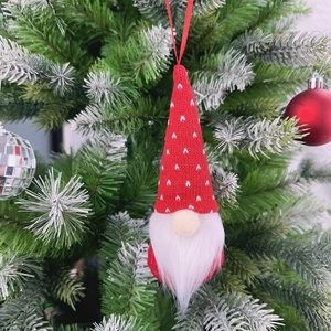 Close-up of red knitted Christmas gnome ornament hanging on a pine tree branch