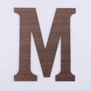 Detail of letter M home decor sign with deep walnut wood grain texture and smooth edges