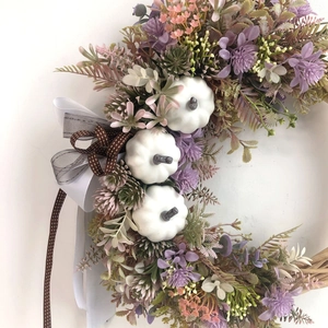 Autumn wreath with white pumpkins, lilac flowers, and elegant ribbons on vine base