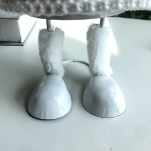Close-up of white plush fur trim and knitted texture on angel ornament metal legs