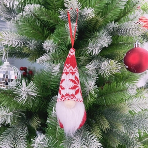 Close-up of a handmade red and white knitted Christmas gnome ornament on a tree