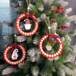 Close-up of three wooden Christmas gnome ornaments hanging on a snowy festive tree