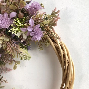 Close-up of handmade grapevine wreath with purple faux flowers and green fern leaves