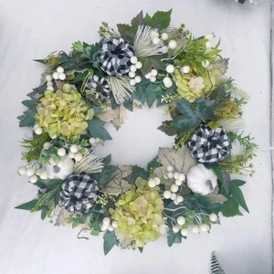Detail of harvest wreath with white pumpkins, green hydrangeas and buffalo plaid bows