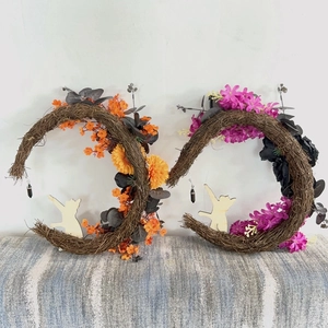 Detail of moon-shaped rattan wreaths with faux flowers and a wooden cat silhouette
