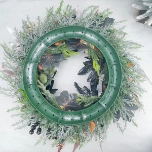 Winter pine wreath with silver snow coating on a green plastic circular frame base