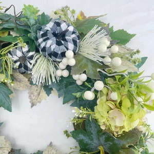 Autumn wreath with black and white buffalo plaid pumpkins and decorative maple leaves