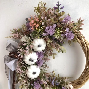 Detail of autumn wreath featuring white mini pumpkins, floral accents, and a triple bow