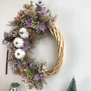 Detail of a handmade floral wreath with white pumpkins and a polka dot ribbon bow