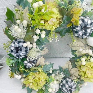 Close-up of harvest wreath featuring white berries and buffalo plaid fabric pumpkins