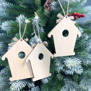 Close-up of three wooden house ornaments with burlap bows hanging on a Christmas tree
