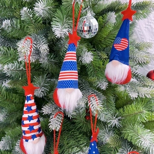 Close-up of patriotic gnome plush ornaments with star patterns hanging on a green tree