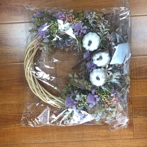 Detail of white decorative pumpkins and purple floral wreath on rustic wooden floor