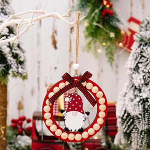 Detail of red wooden Christmas ornament with gnome, wood beads, and plaid bow on snow branch