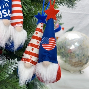 Close-up of USA themed patriotic gnomes with stars and stripes hanging on a green tree