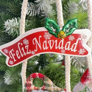 Detail eines roten Feliz Navidad-Banners mit grünen Blättern und einer goldenen Glocke