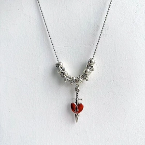 Gothic necklace detail featuring a red enamel heart pierced by a silver metal dagger pendant