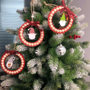 Close-up of wooden gnome ornaments with red beads and plaid bows on a Christmas tree