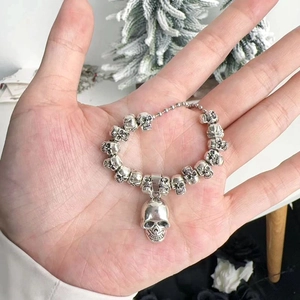 Detail shot of vintage silver skull pendant and chain held in hand for punk jewelry showcase