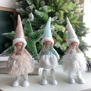Three festive Christmas angel dolls with sequined hats and fluffy skirts on a tree background