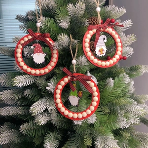 Three red wooden bead Christmas wreaths with gnomes hanging on a snowy tree