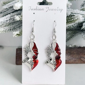 Détail de boucles d'oreilles ailes de cœur gothiques sur carte avec décor de vacances