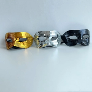 Macro shot of disco ball mirror tiles on reflective gold, silver, and black party masks