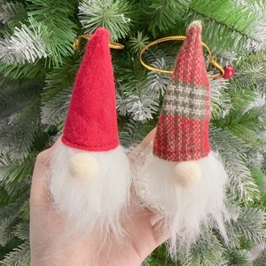 Christmas gnome hanging ornaments with red felt and plaid hats on a lush holiday tree