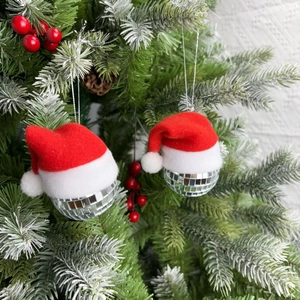 Silver disco ball ornaments with red Santa hats hanging on a festive Christmas tree branch