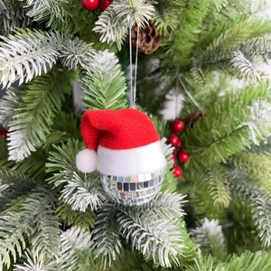 Close-up of a silver mirror disco ball ornament with a red mini Santa hat on a tree