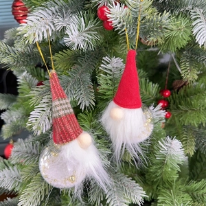 Close-up of festive gnome ornaments with plaid hats hanging on a Christmas tree branch