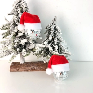 Disco ball Christmas ornaments with red hats and silver mirrors on snowy pine branches