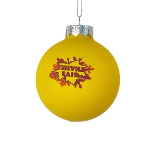 Detailed view of yellow Thanksgiving ornament with maple leaf prints and Give Thanks text