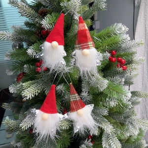 Close-up of four handmade Christmas gnome ornaments with red hats and silver wings on a tree