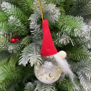 Close-up of a festive gnome Christmas ornament with a red felt hat and golden beads inside