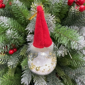 Close-up of Christmas gnome ornament with red felt hat and transparent ball filled with foam