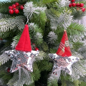 Close-up of sparkling sequin star Christmas ornaments with Santa hats hanging on a tree