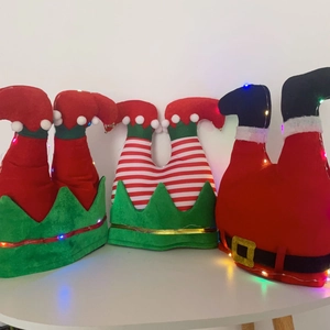 Tre gambe di elfo e Babbo Natale in peluche con stringhe di luci LED colorate su sfondo bianco