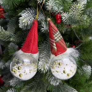 Christmas gnome ornaments with clear snow-filled balls hanging on a pine tree