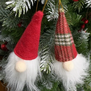 Close-up of handmade Christmas gnome ornaments hanging on a green festive tree