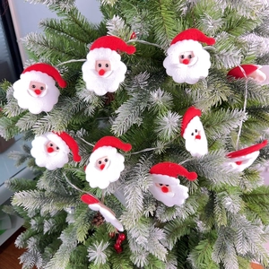 Detailed view of LED string lights featuring plush Santa Claus heads on a green Christmas tree