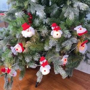 Close-up of plush Santa Claus, snowman, and reindeer LED string lights on a Christmas tree
