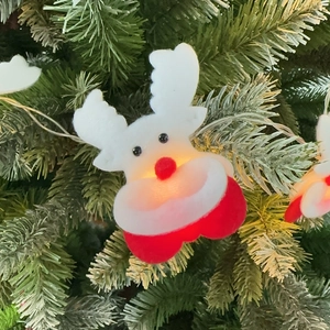Close-up of a plush reindeer Christmas ornament with warm LED lights on a festive tree